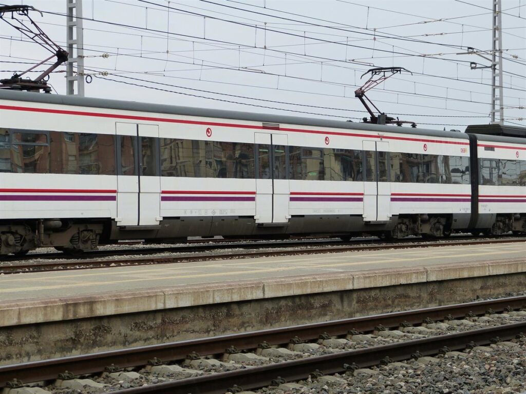 Vías de tren vacías en Arenys de Mar por corte técnico en la R1 con autobuses alternativos al fondo