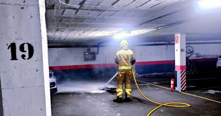 Bomberos extinguiendo llamas en garaje subterráneo con cartones quemados cerca de arqueta de ventilación