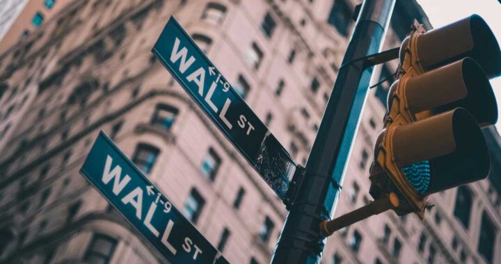 Pantallas de Wall Street mostrando el Dow Jones en rojo (-0,31%) con gráficos de caída por tensión Trump-China en tiempo real