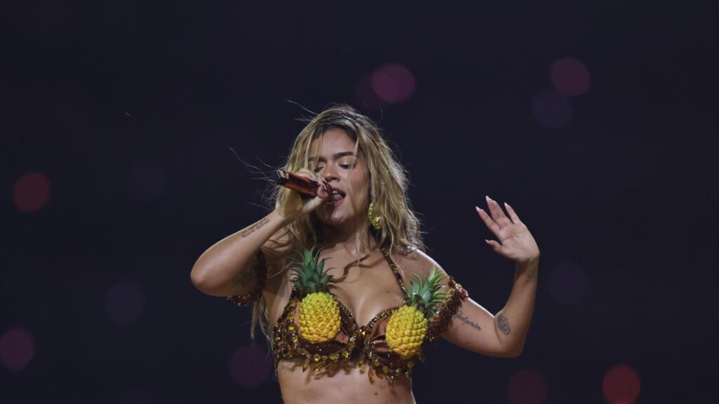 Multitud celebrando con luces de conciertos y cartel de Karol G en estadio ecuatoriano lleno