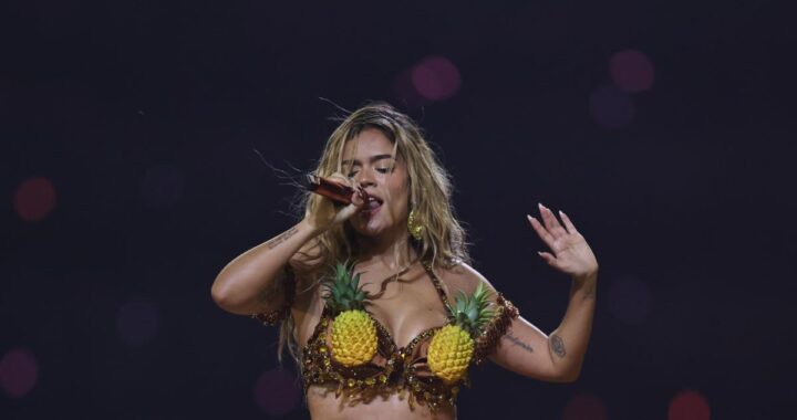 Multitud celebrando con luces de conciertos y cartel de Karol G en estadio ecuatoriano lleno