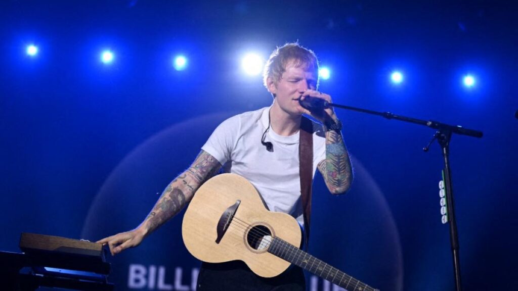 Ed Sheeran en el escenario del Mathematics Tour 2025 con multitudes en un estadio lleno de luces y energía