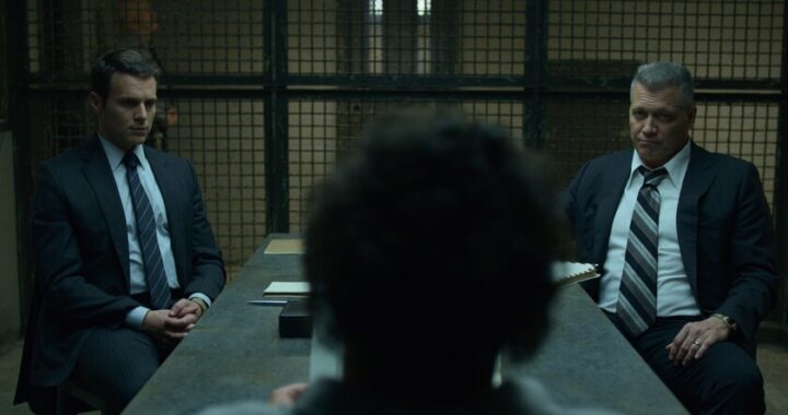 Agentes del FBI entrevistando a un asesino en serie en escena de 'Mindhunter' con estilo visual frío y realista