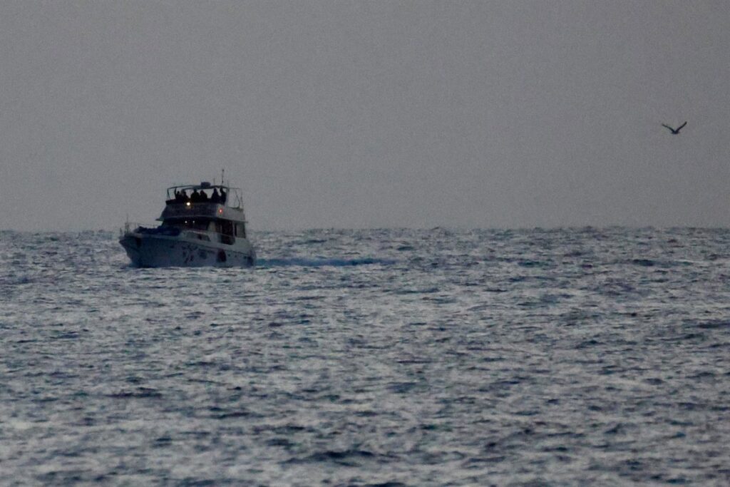 Activistas españoles esposados en puerto israelí tras interceptación de flotilla humanitaria a Gaza con bandera ondeando