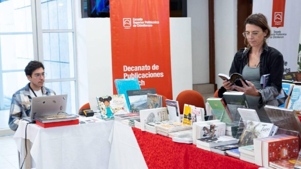 Stand de la Feria del Libro Académico de Quito 2024 con libros expuestos y visitantes explorando novedades editoriales