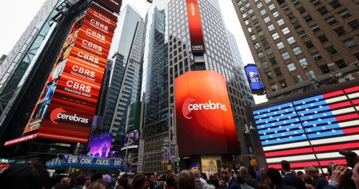 Andrew Feldman, CEO de Cerebras, sostiene el chip WSE-3 durante la OPI en Nasdaq, con gráficos de acciones en alza al fondo