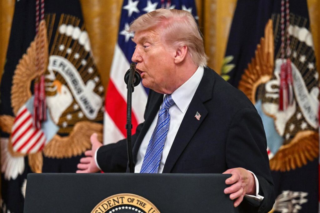 Donald Trump en rueda de prensa con mapa de Oriente Medio y bandera de EE.UU. al fondo, hablando de estrategia militar contra Irán