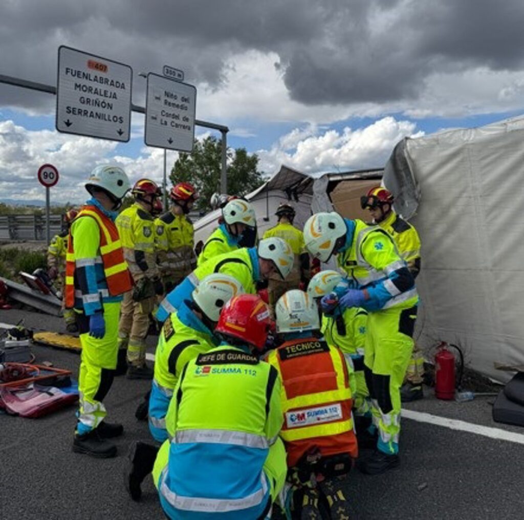 Bomberos usando herramientas hidráulicas para rescatar conductor atrapado en camión volcado en carretera M-407 con 40 toneladas de carga
