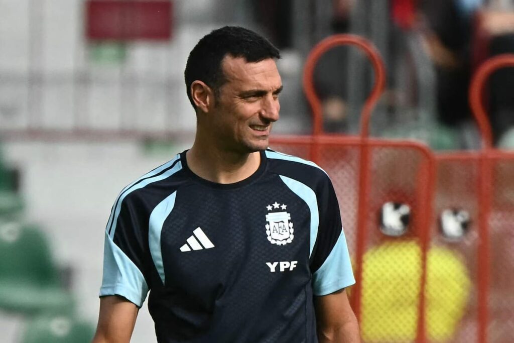 Lionel Scaloni analizando a jóvenes promesas argentinas en entrenamiento previo al Mundial 2026 con fondo de bandera albiceleste