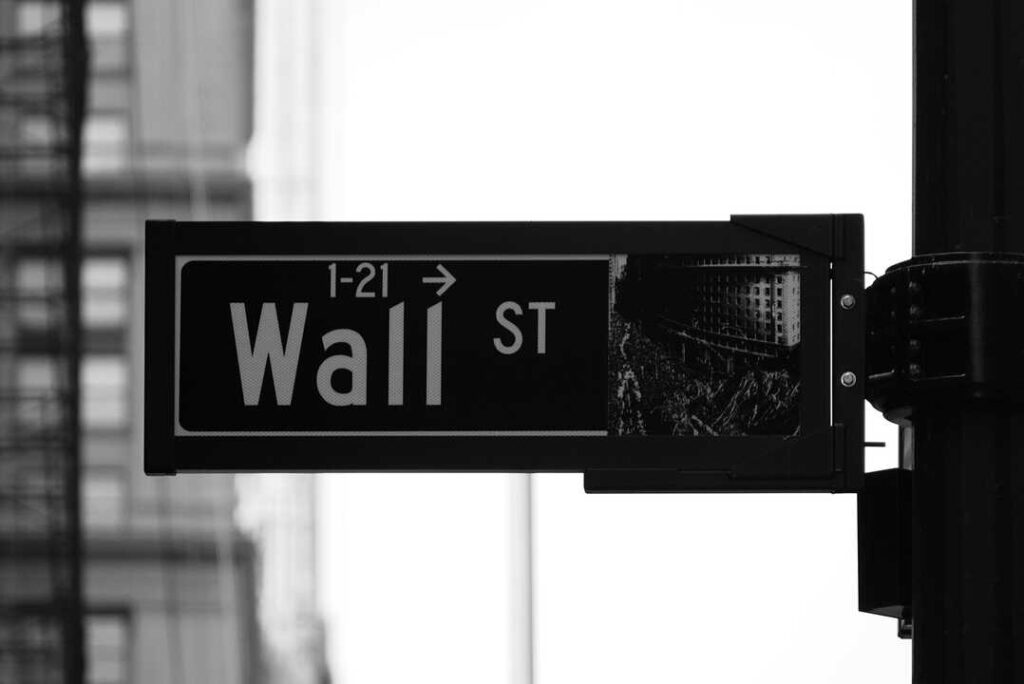 Gráfico comparativo de Wall Street en caída y IBEX 35 en alza con datos de Nasdaq, S&P 500 y Dow Jones