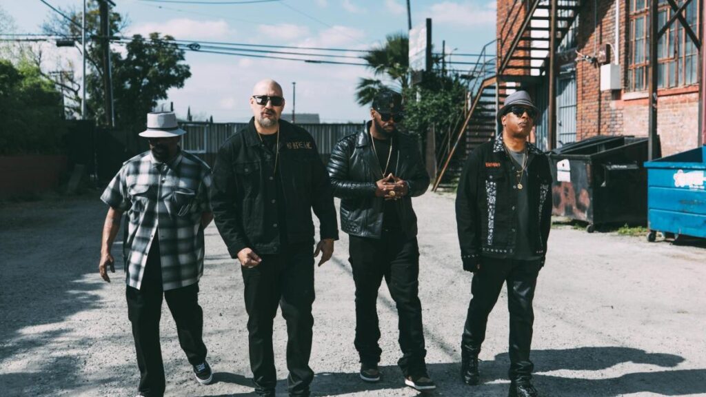 Cypress Hill en foto oficial de gira 2026 con fondo de escenario y luces de concierto