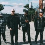 Cypress Hill en foto oficial de gira 2026 con fondo de escenario y luces de concierto