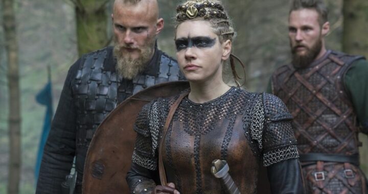 Travis Fimmel como Ragnar Lothbrok en escena épica de 'Vikingos' con barco dragón y paisaje nórdico