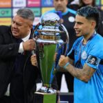Mapa mundial con 15 banderas destacadas simbolizando los candidatos al título en el Mundial 2026 y trofeo en el centro