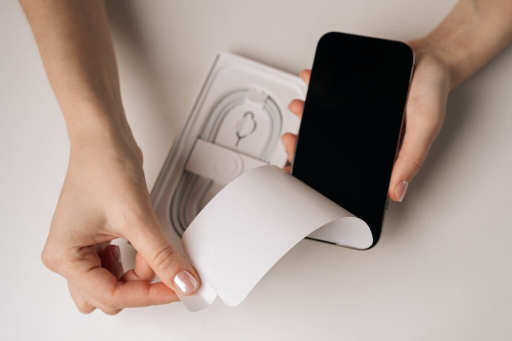 Manos sosteniendo un celular con etiqueta 'IMEI clonado' junto a un sello de Enacom tachado, alertando sobre contrabando