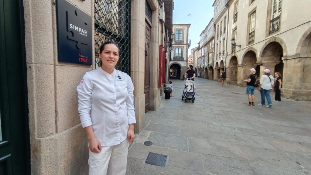 Claudia Merchán, chef ecuatoriana, sonríe en la cocina de Simpar con su delantal y la placa de estrella Michelin 2025