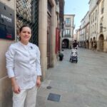 Claudia Merchán, chef ecuatoriana, sonríe en la cocina de Simpar con su delantal y la placa de estrella Michelin 2025