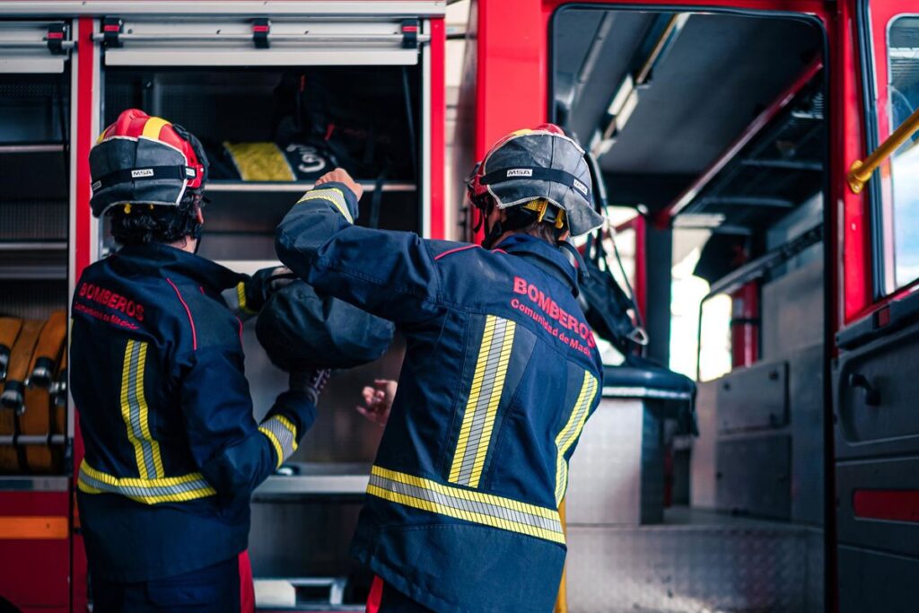 Bomberos trabajando de noche con mangueras para apagar incendio en arizónica de madera en Boadilla