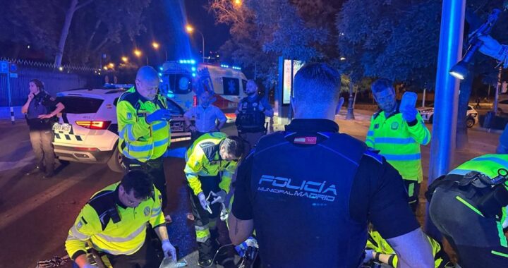 Motorista en el suelo tras caída nocturna en Paseo de la Castellana con ambulancia de fondo y luces de emergencia