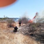 Bomberos y helicóptero combatiendo el incendio en el cauce del río Andarax en Almería con viento de levante