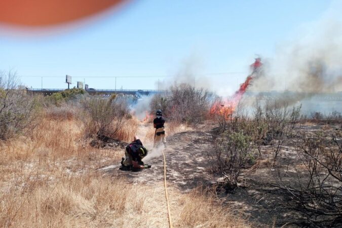 Bomberos y helicóptero combatiendo el incendio en el cauce del río Andarax en Almería con viento de levante