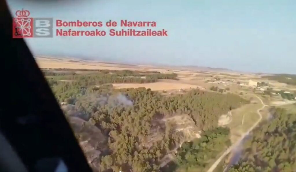 Bomberos combatiendo incendio forestal en pinar cerca de las ruinas romanas de Las Vistillas en Lerín