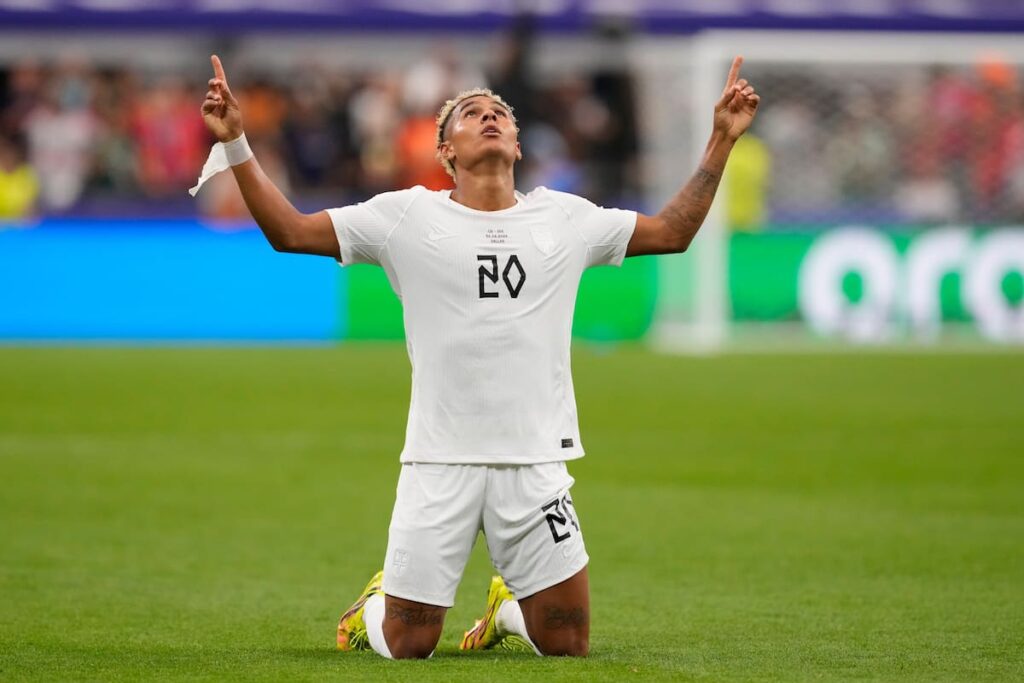 Antonio Nusa celebra su gol espejo con Noruega mientras sostiene su libro 'Alt starter med en drøm'